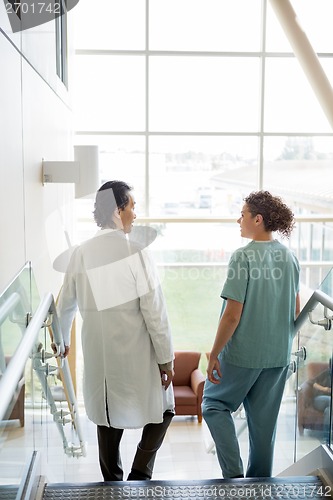 Image of Doctor And Nurse Conversing While Walking Down Stairs In Hospita