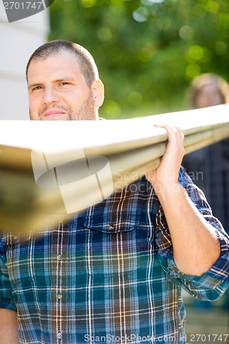 Image of Carpenter Carrying Wooden Planks Outdoors