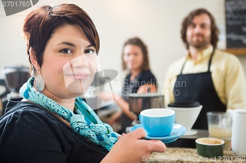 Image of Woman Holding Coffee Cup With Owners in cafe