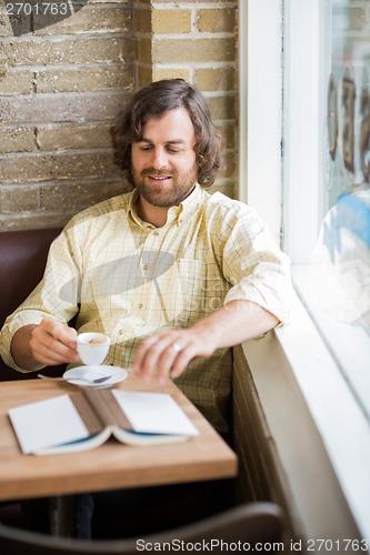 Image of Man With Coffee Cup And Book In Cafeteria