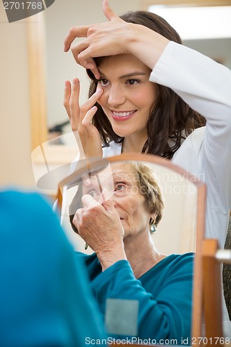 Image of Eyecare Doctor Teaching Senior Woman To Insert Contact Lens