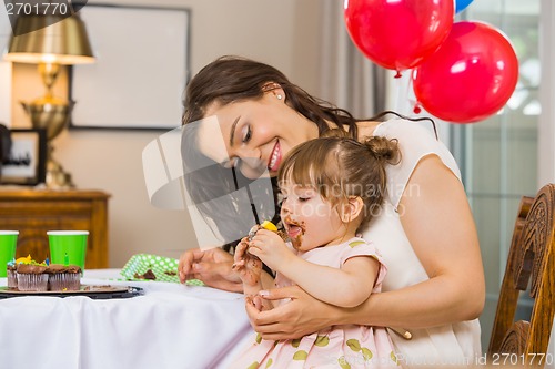 Image of Mother Looking At Birthday Girl Eating Cupcake