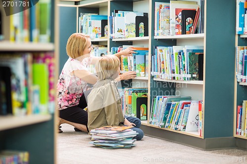 Image of Teacher Assisting Boy In Selecting Books In Library