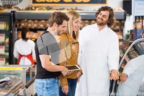 Image of Worker Assisting Couple At Butcher's Shop