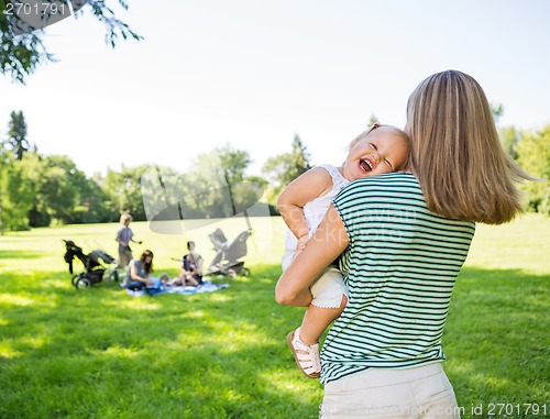 Image of Mother Carrying Cheerful Daughter In Park