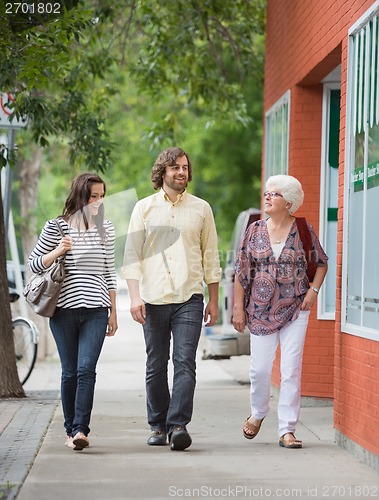 Image of Smiling Friends Walking On Pavement