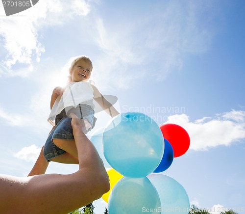 Image of Mother Lifting Daughter Against Cloudy Sky