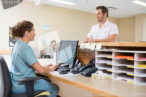 Image of Nurse And Patient Conversing At Reception Desk