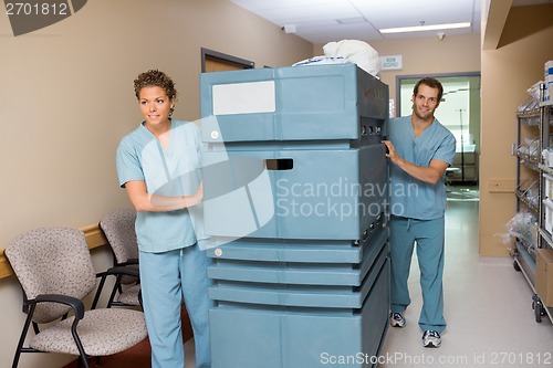 Image of Nurse Pushing Trolley While Colleague Assisting Him In Hallway