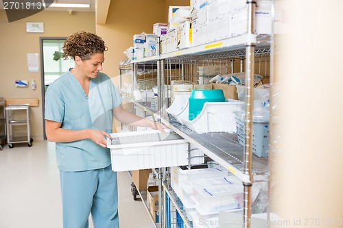 Image of Nurse Arranging Container On Shelf In Storage Room