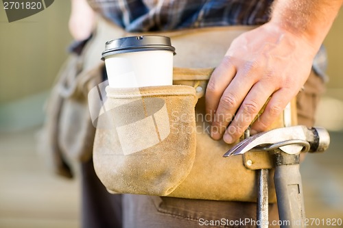 Image of Disposable Coffee Cup And Hammer On Carpenter's Tool Belt