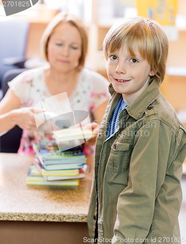 Image of Boy With Librarian Scanning Books At Library Counter