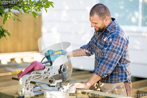 Image of Carpenter Cutting Wood Using Table Saw At Construction Site