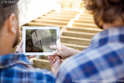 Image of Worker Pointing At Digital Tablet While Coworker Holding It