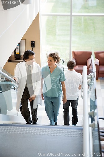 Image of Doctor And Nurse Discussing While Walking On Stairs