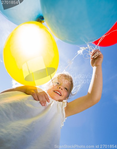 Image of Happy Girl Holding Balloons Against Sky