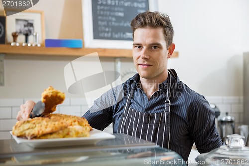 Image of Confident Cafe Owner Holding Sweet Food In Tongs