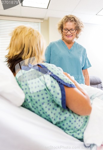 Image of Happy Nurse Looking At Newborn Babygirl With Mother In Hospital