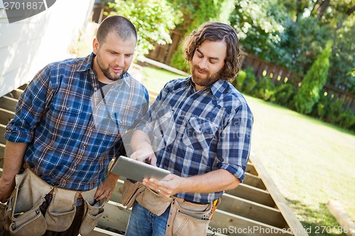 Image of Workers Discussing Project On Digital Tablet At Site