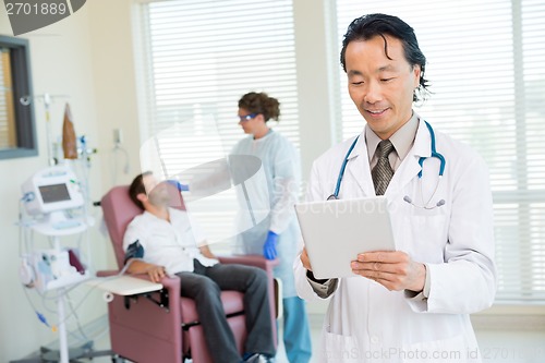 Image of Doctor Using Digital Tablet In Chemo Room