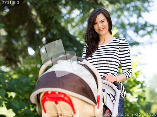 Image of Beautiful Woman Pushing Stroller In Park