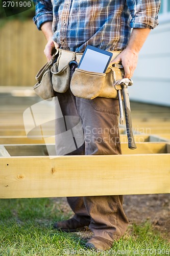 Image of Carpenter With Tablet Computer And Hammer In Tool Belt