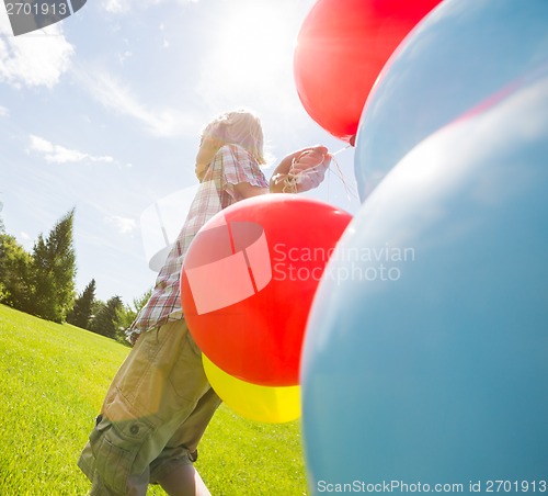 Image of Boy With Balloons Walking In Green Meadow