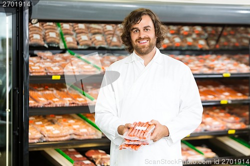 Image of Happy Salesman Holding Meat Packages At Counter