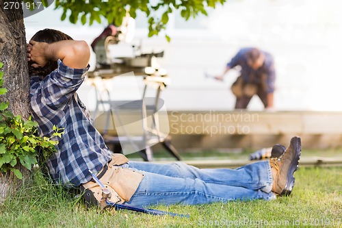 Image of Manual Worker Leaning On Tree Trunk