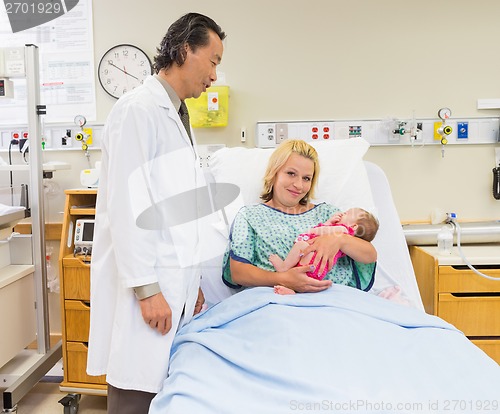 Image of Mother Holding Newborn Babygirl While Doctor Standing By In Hosp