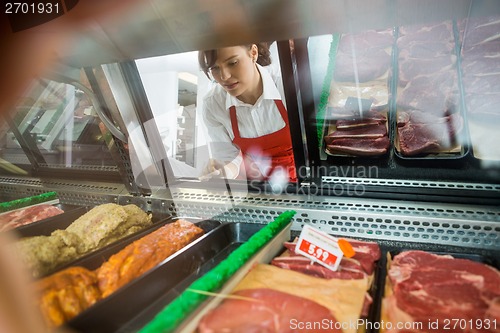 Image of Saleswoman Looking At Variety Of Meat Displayed In Shop