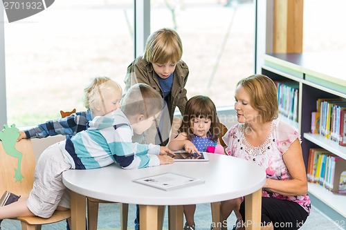 Image of Teacher With Students Using Digital Tablets In Library