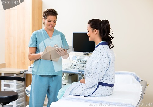 Image of Nurse Writing Notes With Patient Sitting On Bed