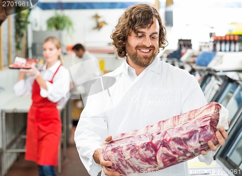 Image of Happy Butcher Looking At Meat Package