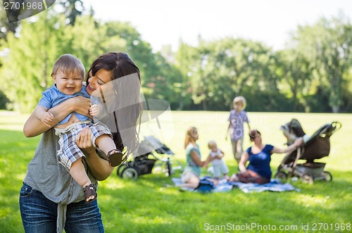 Image of Mother Carrying Cheerful Baby Boy At Park