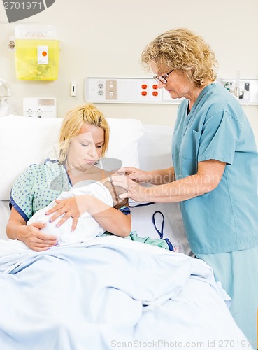 Image of Nurse Assisting Woman In Breast Feeding Baby In Hospital