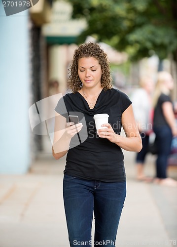 Image of Woman With Coffee Cup Using Smartphone On Pavement