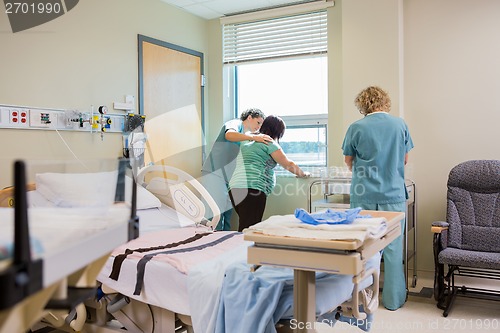 Image of Nurse Comforting Pregnant Woman At Window In Hospital Room