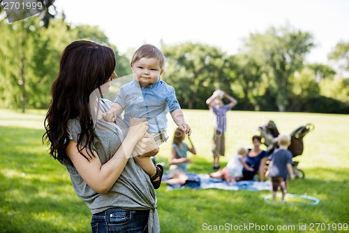 Image of Happy Mother Carrying Son In Park