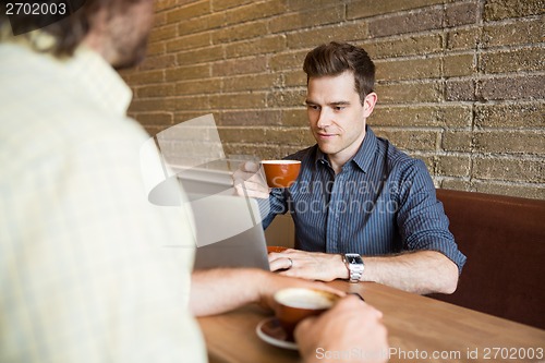 Image of Man and Friend in Coffee Shop Using Computer