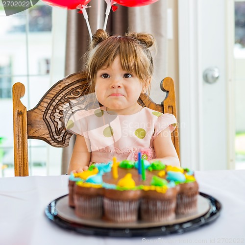 Image of Birthday Girl Sitting In Front Of Cake