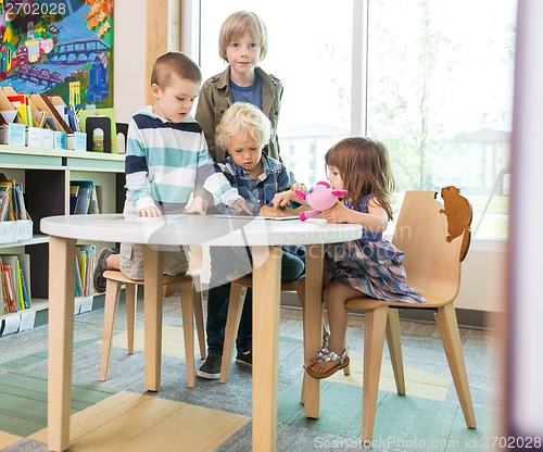 Image of Children Using Digital Tablet At Table In Library