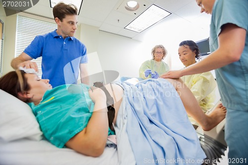 Image of Man Looking At Medical Team Operating Pregnant Woman