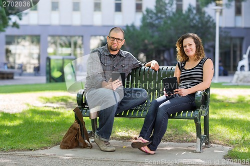 Image of Confident Students Sitting On Bench At University Campus