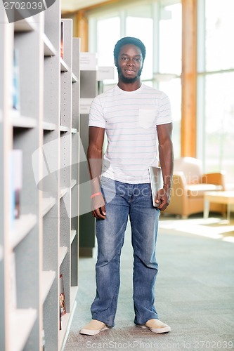 Image of Student With Digital Tablet Standing By Bookshelf In Library