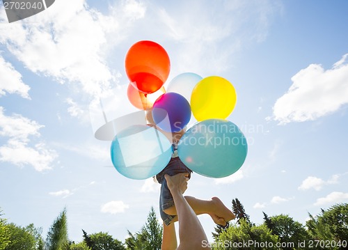Image of Mother And Daughter Holding Balloons Against Sky