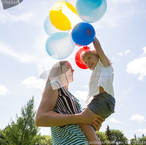 Image of Mother And Daughter Playing With Balloons Against Sky