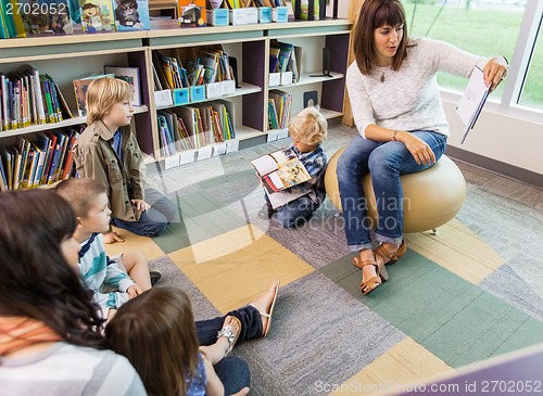 Image of Teacher Reading Book To Children In Library