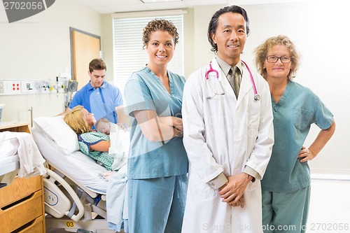 Image of Confident Medical Team With Newborn Baby And Parents In Backgrou