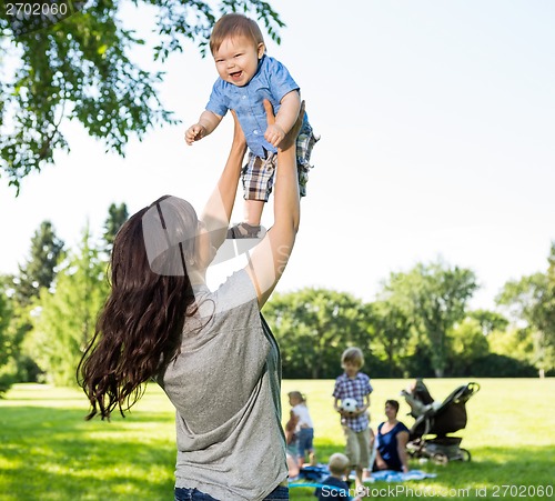 Image of Playful Mother Lifting Baby Boy In Park